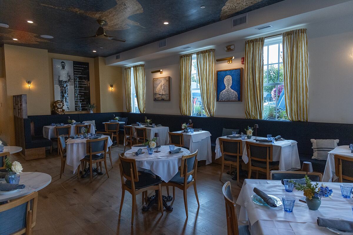 A dining room at Marée set with white linens, blue glassware, and seasonal flowers