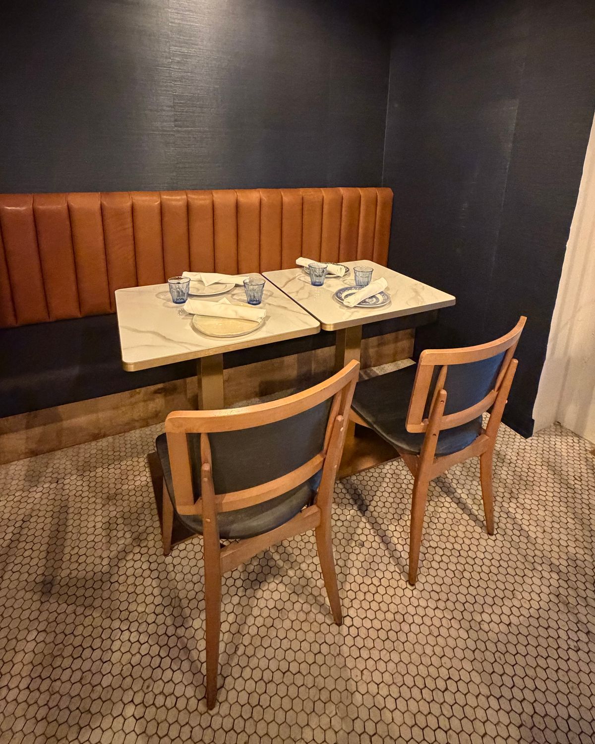 A leather banquette and marble tables inside the Vault at Marée